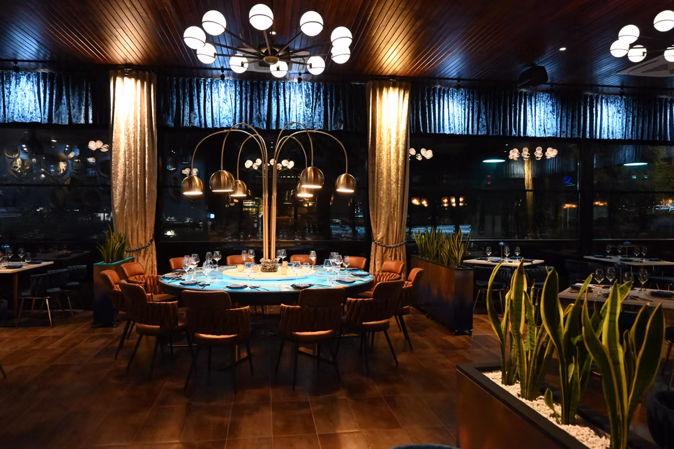 The main dining room at night, The Pearl table lit beneath its brass pendants